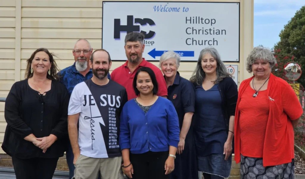 Group standing outside Hilltop Christian Church sign